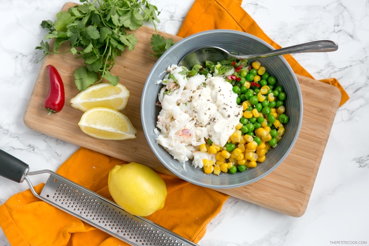 lobster mixed with sweetcorn and peas in a bowl,  lemon, chili and grater next to the bowl