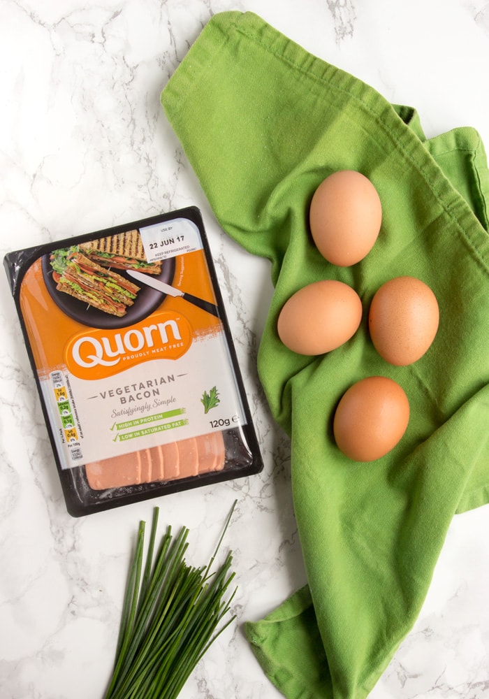 eggs on a green napkin, chives on the bottom side and quorn vegetarian bacon packagin on the left side
